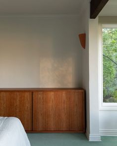 a bed sitting next to a window in a room with green carpeted flooring