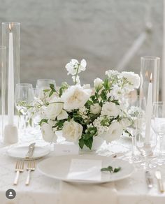 a table set with white flowers and candles