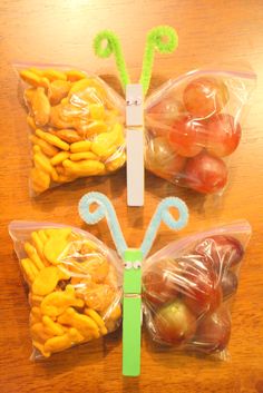 two plastic bags filled with fruits and vegetables sitting on top of a wooden table next to each other