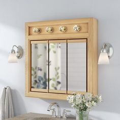 a bathroom with a sink, mirror and flowers on the counter top in front of it