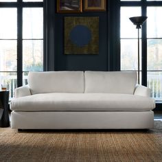 a white couch sitting in front of two windows