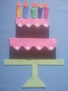 a three tiered cake with candles on it is cut out of felt and placed on a blue background