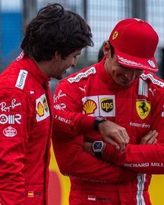 two men standing next to each other on a race track