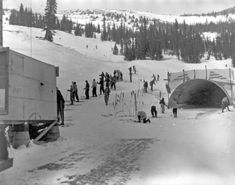 an old black and white photo of people on skis in the snow near a tunnel