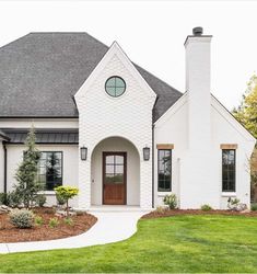 a white brick house with a brown door and two windows on the side of it