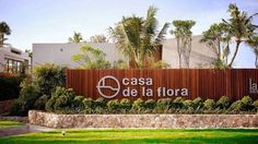 a sign that reads casa de la flora in front of some palm trees and bushes