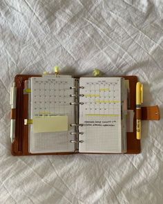 an open planner and pen sitting on top of a bed