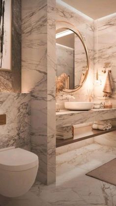 a modern bathroom with marble walls and flooring, including a large round mirror above the toilet