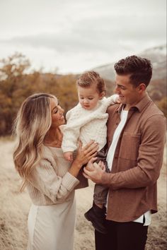 a man and woman holding a baby in their arms