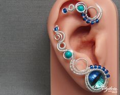 a fake ear is adorned with blue beads and silver wire, as well as an earring