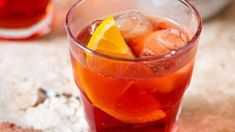 a close up of a drink in a glass with ice and lemon wedges on the rim