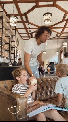 a man standing over two children sitting on a couch