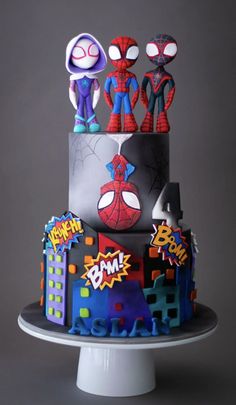 a three tiered cake decorated with cartoon characters on the front and sides, including spider - man