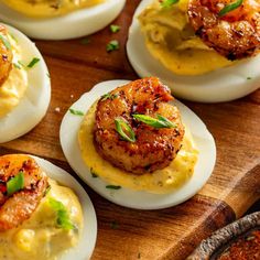 deviled eggs topped with shrimp and grits on a wooden board, ready to be eaten