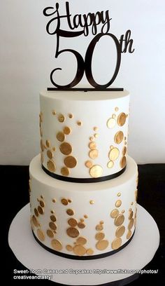 a white cake with gold confetti on it and the words happy 50th written in black