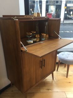 a wooden cabinet sitting on top of a hard wood floor next to a white stool