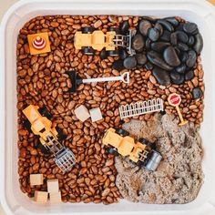 a container filled with lego construction vehicles on top of coffee beans