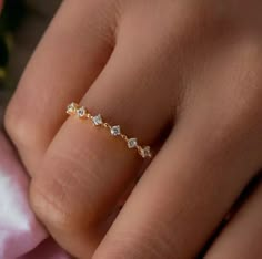 a woman's hand wearing a gold ring with five small white diamonds on it