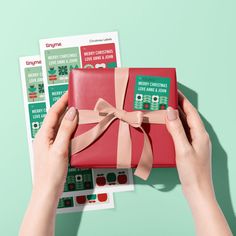 a woman's hands holding a red gift box with a pink ribbon on it