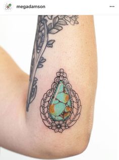 a woman's arm with a tattoo on it and a stone in the middle