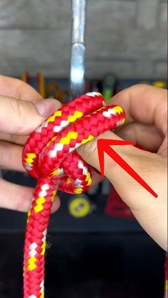 a person tying a red and yellow rope with an arrow pointing to the right side