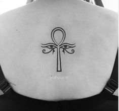 an egyptian cross tattoo on the back of a woman