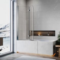 a bath tub sitting next to a large window in a room with wooden flooring