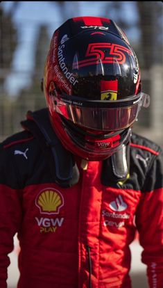 a man wearing a red and black racing suit with a helmet on top of his head