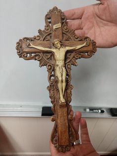 a wooden crucifix in the shape of a jesus on a cross is being held by a hand