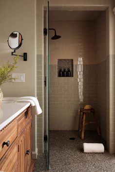 a bathroom with a walk in shower sitting next to a sink and wooden cabinetry