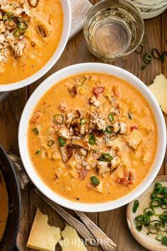 two bowls of soup on a table with cheese and crackers next to each other