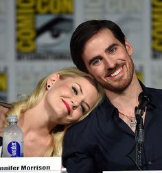 a man and woman are posing for a photo in front of a comic book panel