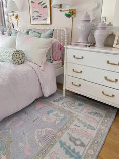 a white bed sitting in a bedroom next to a dresser with drawers and lamps on top of it