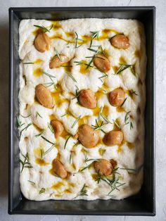 a square pan filled with mashed potatoes topped with olives and green garnish