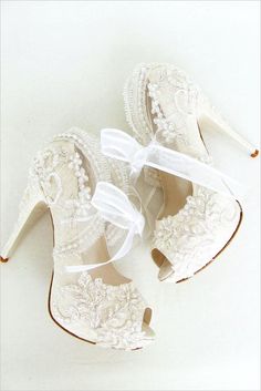 two pairs of white shoes with bows on the heel and lace detailing, all tied together