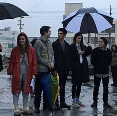 a group of people standing in the rain with umbrellas