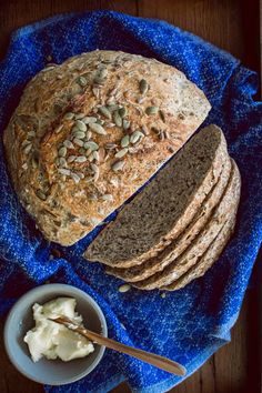 a loaf of bread sitting on top of a blue towel next to a bowl of butter