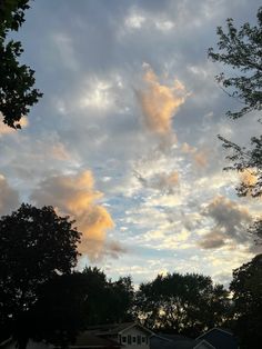 the sky is full of clouds and some houses are in the foreground with trees on either side