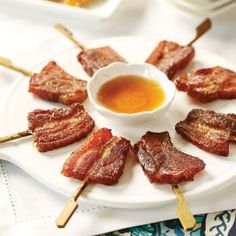 bacon skewers on a plate with dipping sauce