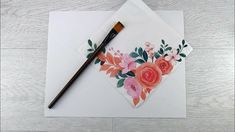 a piece of paper with flowers on it and a paintbrush resting on top of it