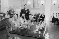 a bride and groom sitting at a table in front of their guests during a wedding reception