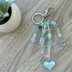 a bunch of glass beads and charms on a table next to a potted plant