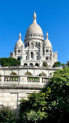 the top of a large building with domes on it's sides and trees in front