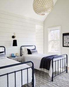 two beds in a bedroom with white walls and wood floors