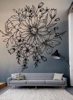 a living room with a gray couch and large flower wall decal on the wall