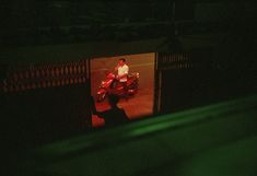 a man standing next to a red motorcycle in the dark with green lights on it