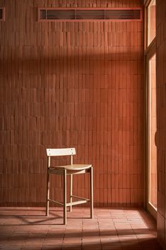 a chair sitting in front of a brick wall with sunlight coming through the open window