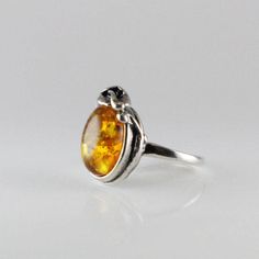 Amber ring with sterling silver oval shape Baltic amber jewelry cognac, delicate design with small silver leafs ornated wire around stone Classic antique style Amber ring Oval shape cabochon 925e sterling silver handmade sparkling light cognac (honey) color Baltic amber COLORS : the real stone color is cognac Amber same ring has the picture the darker image more cognac then yellow Solid sterling bezel silver 925e handmade  Dimensions Stone size : 14 x 10 mm Length : 19 mm  Width : 14 mm  Height : 7.2 mm Weight : 2.9 gr Minimalist Amber Sterling Silver Jewelry, Sterling Silver Amber Ring, Amber Oval Cabochon Sterling Silver Ring, Adjustable Sterling Silver Amber Ring, Silver Baltic Amber Oval Jewelry, Honey Color, Baltic Amber Jewelry, Dark Images, Sparkling Lights