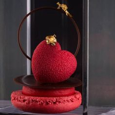 a heart - shaped object is sitting on top of two red cookies in front of a glass case