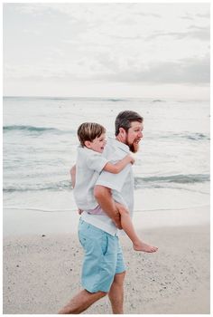 a man carrying a young boy on the beach